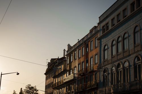 Free A picturesque view of Lisbon's historic architecture during sunset, displaying colorful facades and classic street lamps. Stock Photo