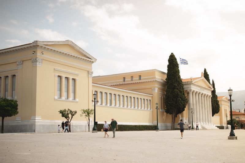 Zappeion Hall's neoclassical architecture in Athens featuring columns and Greek flag.