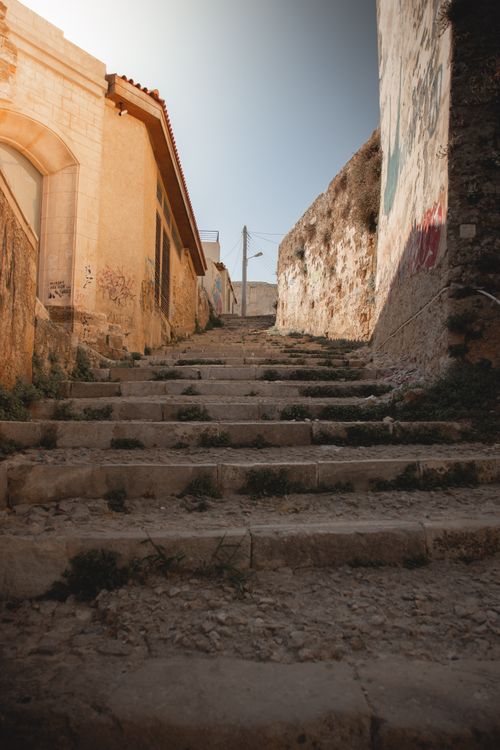 Free A scenic view of aged stone steps leading through a traditional Greek village street. Stock Photo