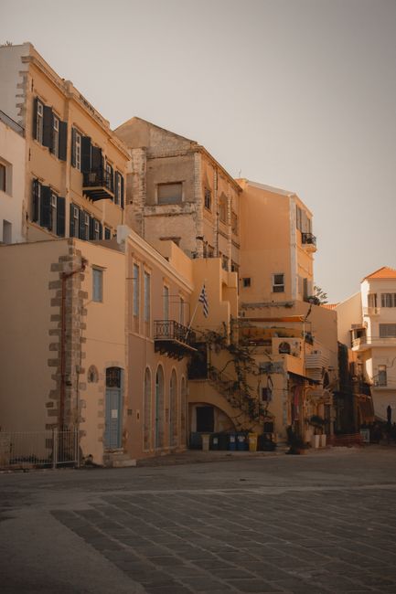 Quaint buildings line a historic street in Chania, Greece with warm lighting and classic architecture.