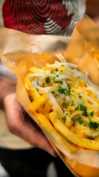 Delicious close-up of cheesy loaded french fries garnished with herbs, perfect for fast food enthusiasts.