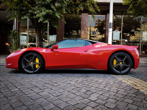 Free Luxurious red supercar parked on a cobblestone street in Porto, Portugal, showcasing sleek design under daylight. Stock Photo