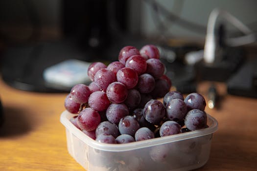 Close-up of fresh red grapes in a plastic container, showcasing juicy and delicious fruit.