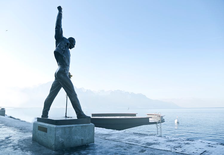 Gray Metal Statue Of Man Raising Hand Near Dock