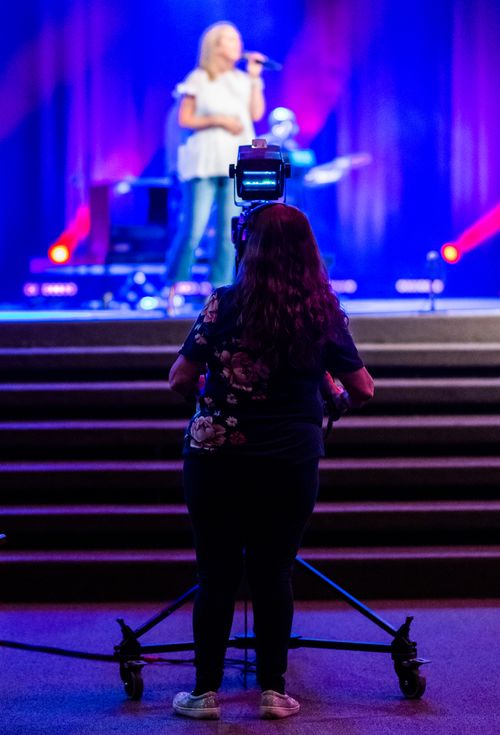 Free A camerawoman records a live concert on stage, emphasizing production and media. Stock Photo