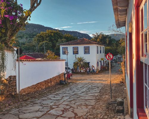 Free Cobblestone street in Tiradentes, Brazil, showcasing colonial architecture against a backdrop of lush hills. Stock Photo