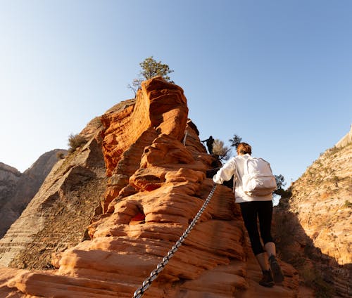 Man and Woman Walking on Brown Rocky Mountain