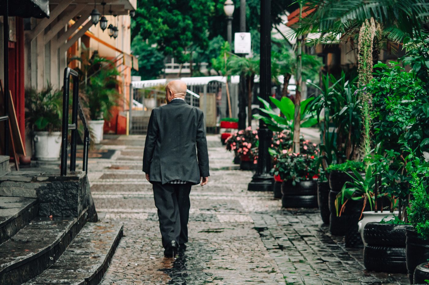 A man in a suit walking a wet cobbled street — photo by Thom Gonzalez on Pexels
