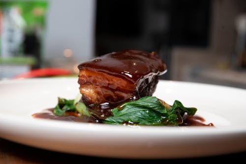 Close-Up Shot of Delicious Braised Pork on White Ceramic Plate