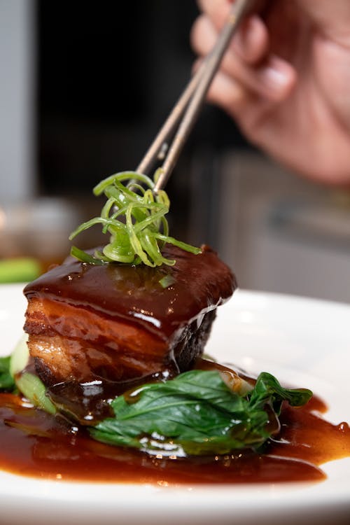 A Person Holding Silver Chopstick with Green Vegetables