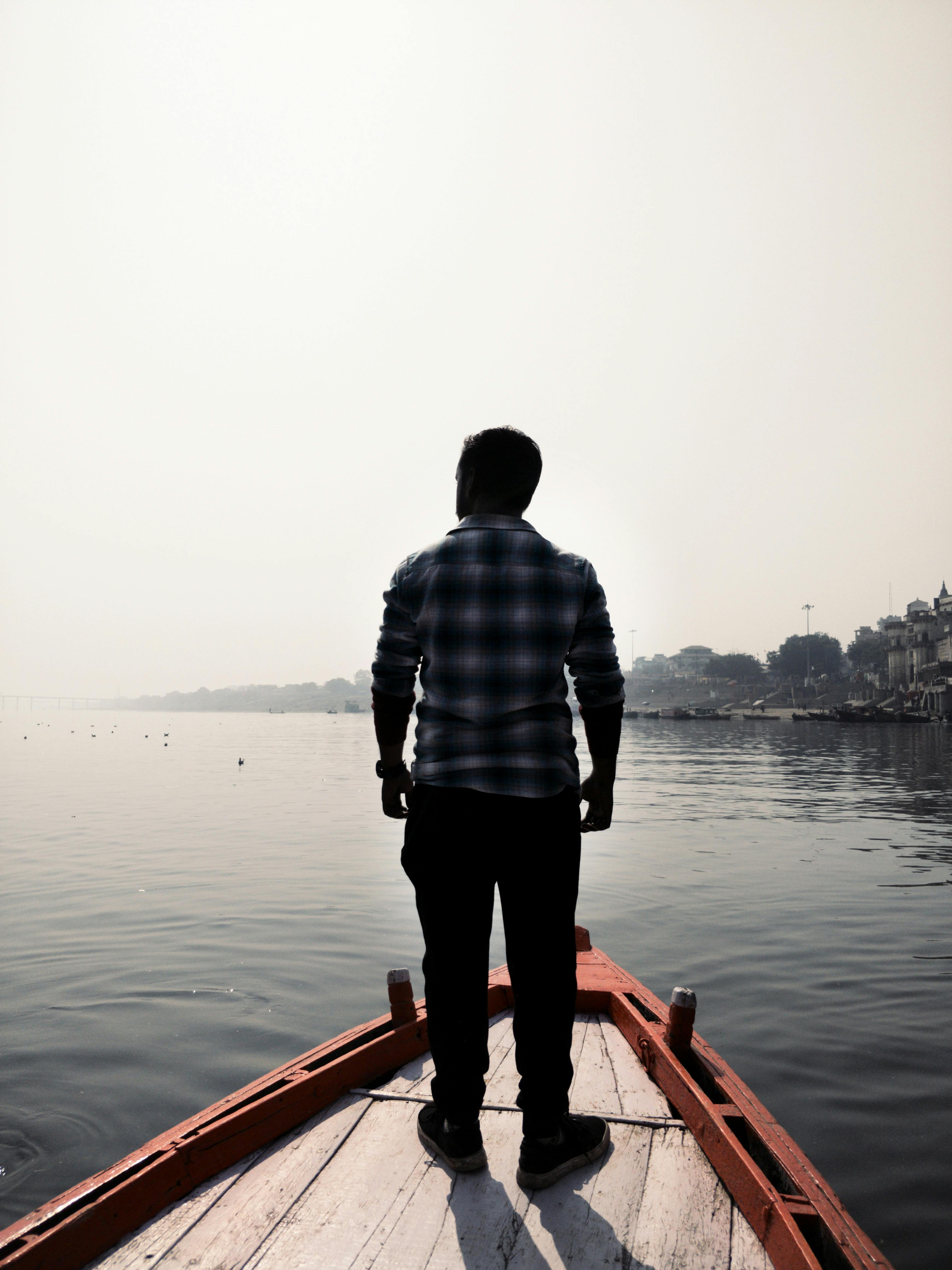Man standing on a wooden boat. | Photo: Pexels