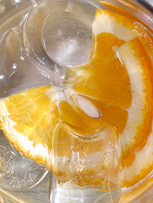 Macro shot of an orange slice submerged in ice water, showing freshness and vibrant color.