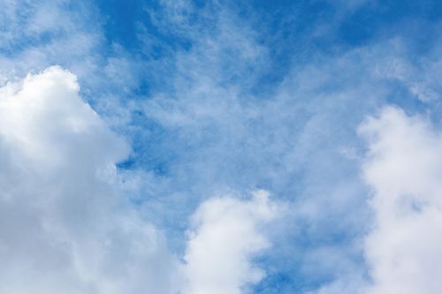 Free A serene view of fluffy white clouds against a vibrant blue sky, perfect for depicting clear weather. Stock Photo
