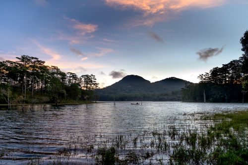 Free Peaceful lake and mountain scene during sunrise with picturesque clouds and lush trees. Stock Photo