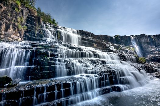 A stunning and serene waterfall flowing over tiered rocks in a natural landscape.