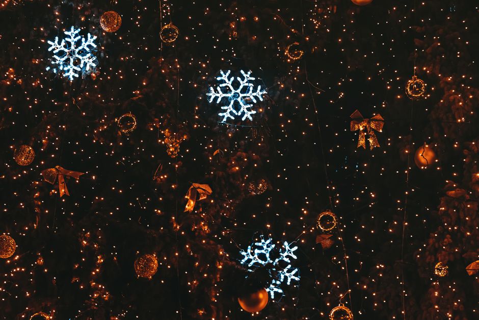 Illuminated Christmas decorations with snowflakes and golden ornaments on black background.