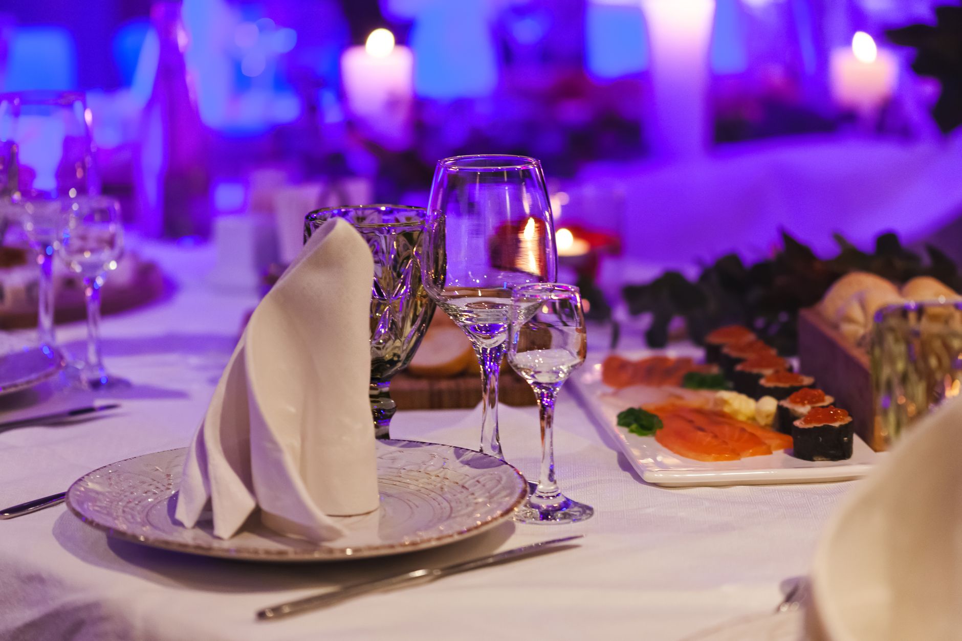 Sophisticated table setting with sushi platter, candlelights, and elegant glassware, perfect for fine dining ambiance.