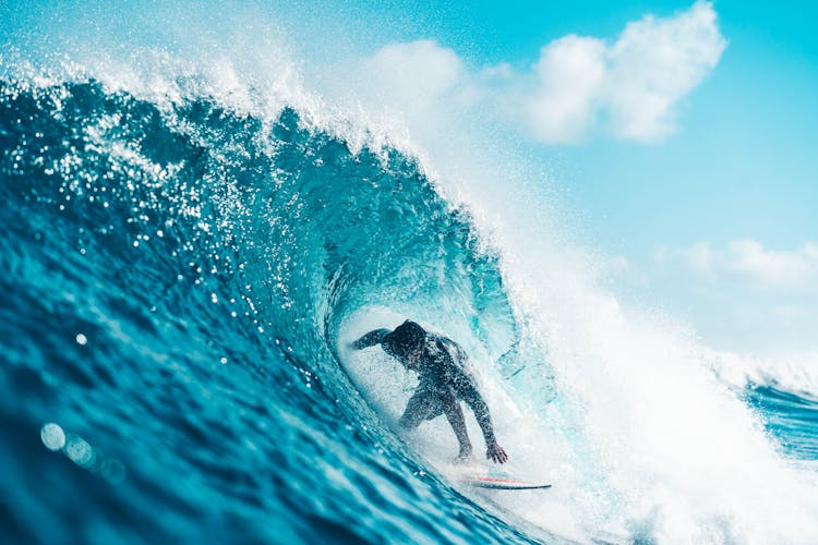 Unrecognizable Energetic Surfer Riding Azure Sea Wave