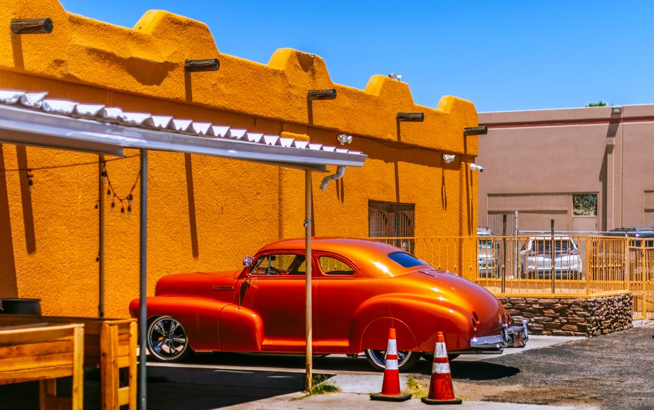 Vintage orange Chevrolet coupe parked by a vibrant wall in Tucson, Arizona.