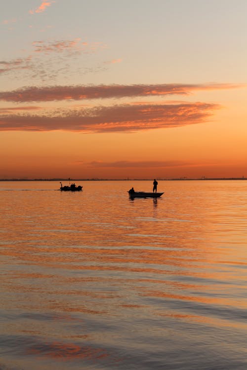 Free Silhouette of a Person Riding a Boat on Sea during Sunset Stock Photo