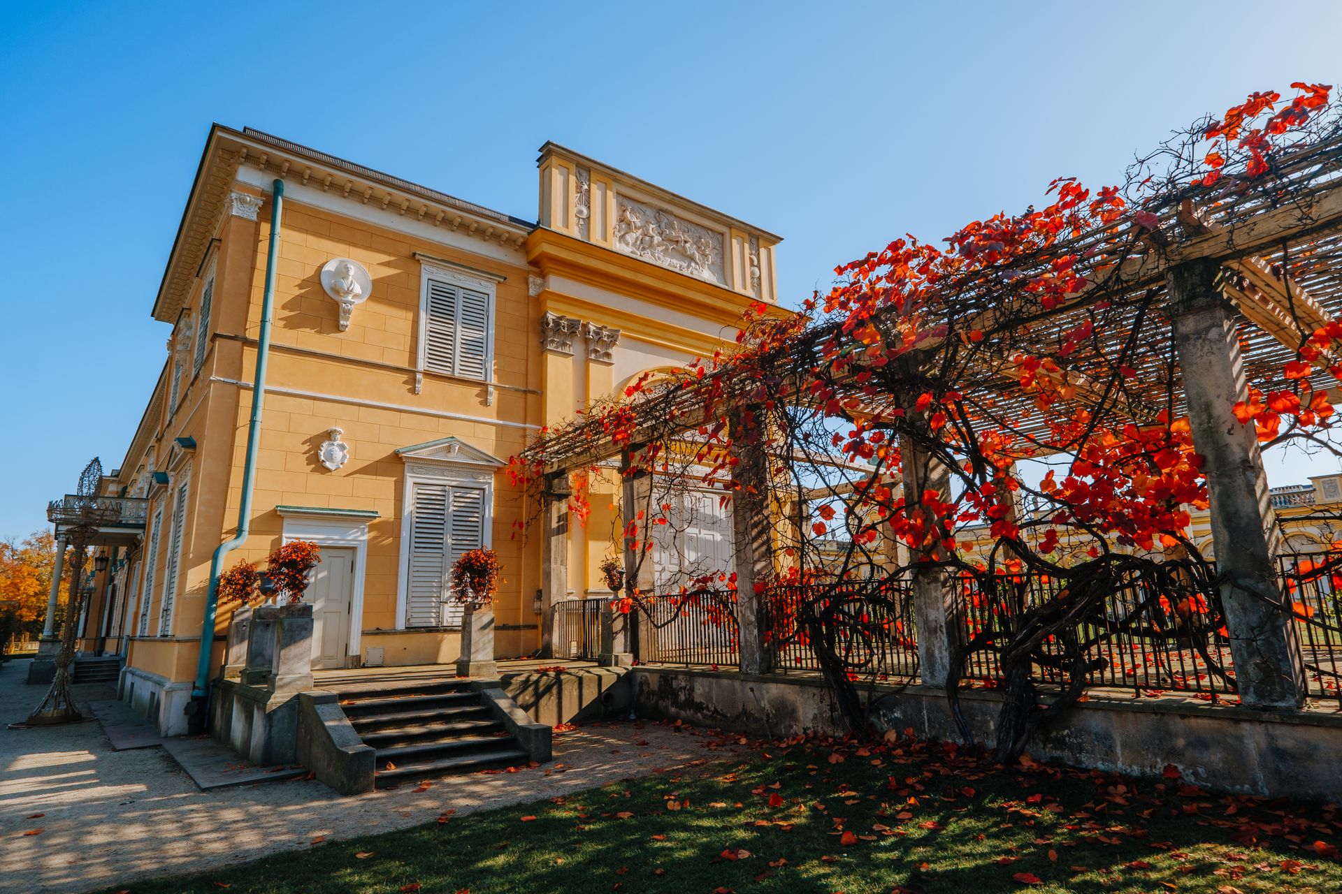 Exterior view of historic building with ivy-covered pergola in Wilanow, Warsaw during autumn.