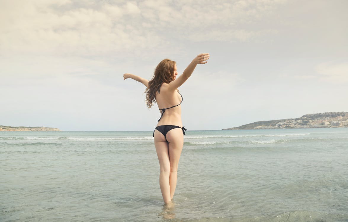 Free Woman in Black Bikini Standing on Shore Stock Photo
