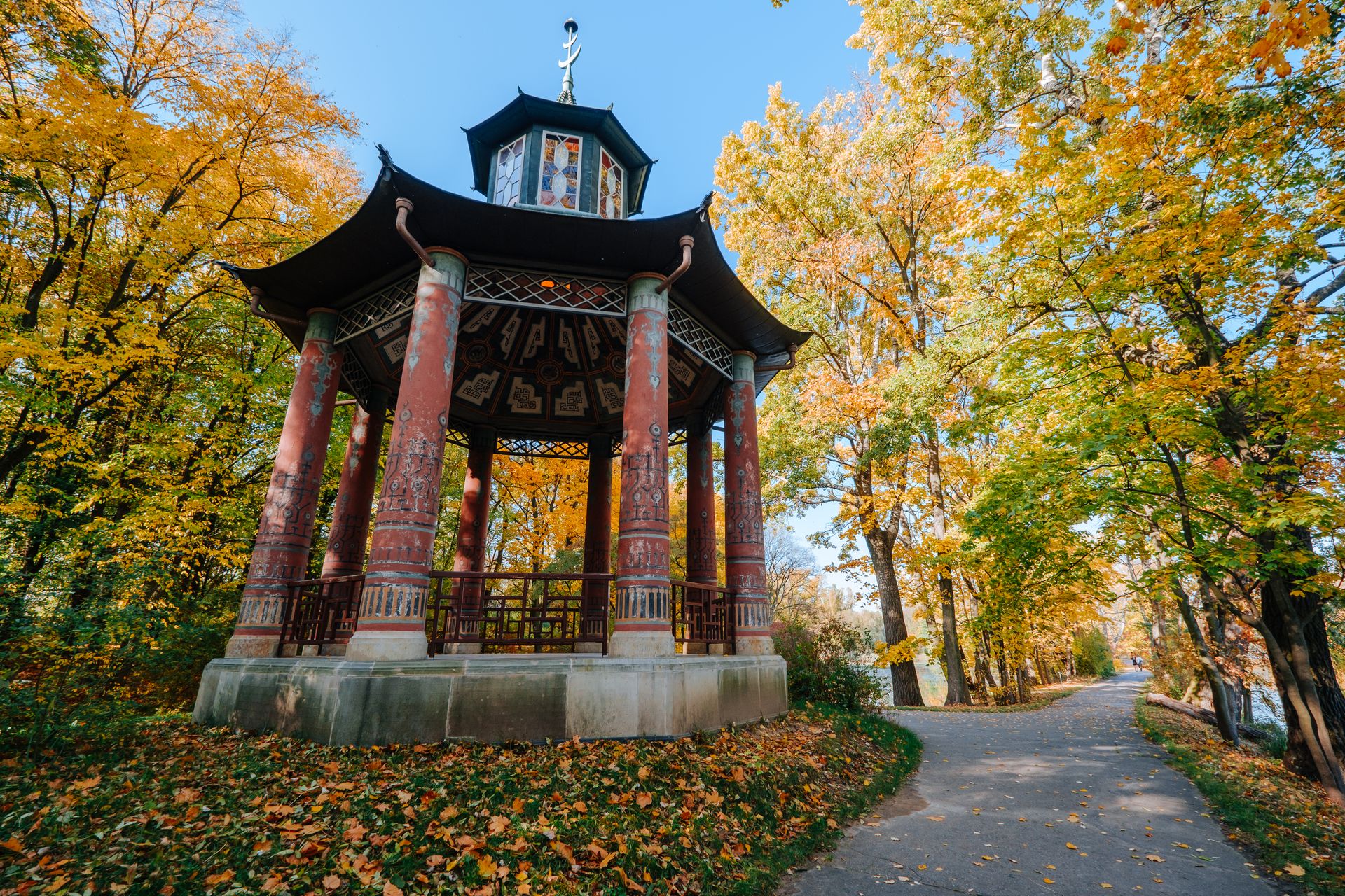 Traditional gazebo amidst vibrant autumn foliage in a serene park setting.