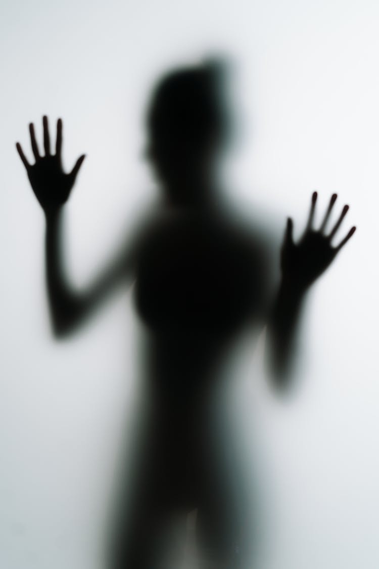 A Silhouette Of Person Touching A Frosted Glass