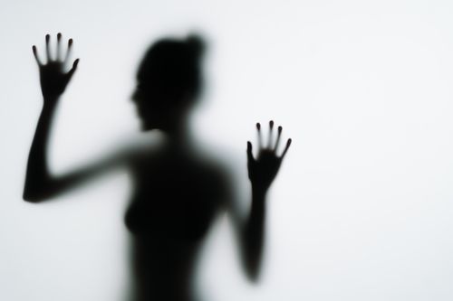 Free Artistic silhouette of a woman pressing her hands against frosted glass, creating a mysterious effect. Stock Photo