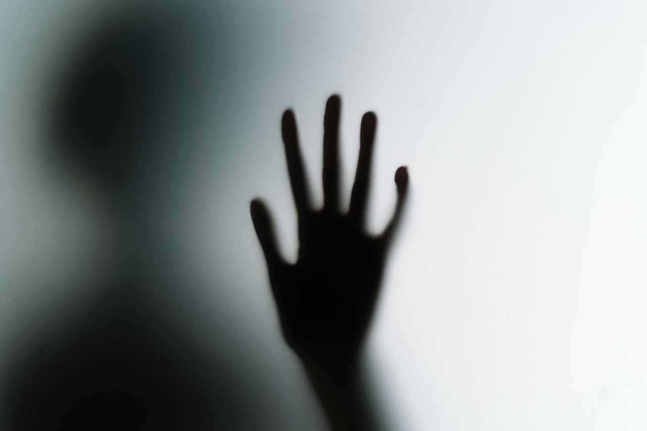 silhouette of a hand pressed against frosted glass creating a mysterio