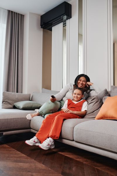 A mother and daughter enjoy a cozy moment on a modern living room sofa.