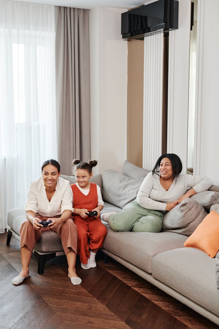 A Happy Family Sitting On The Couch While Playing Video Game