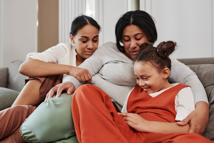 Smiling Women Sitting With Child On Couch