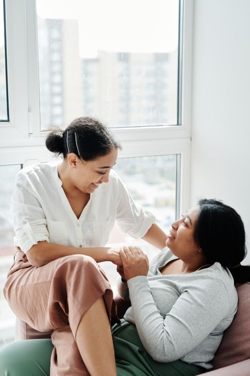 Free Lesbian couple smiling and holding hands at home, exuding love and happiness in a cozy setting. Stock Photo