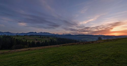 Free Enjoy the serene view of a grass field overlooking a breathtaking mountain sunset. Stock Photo