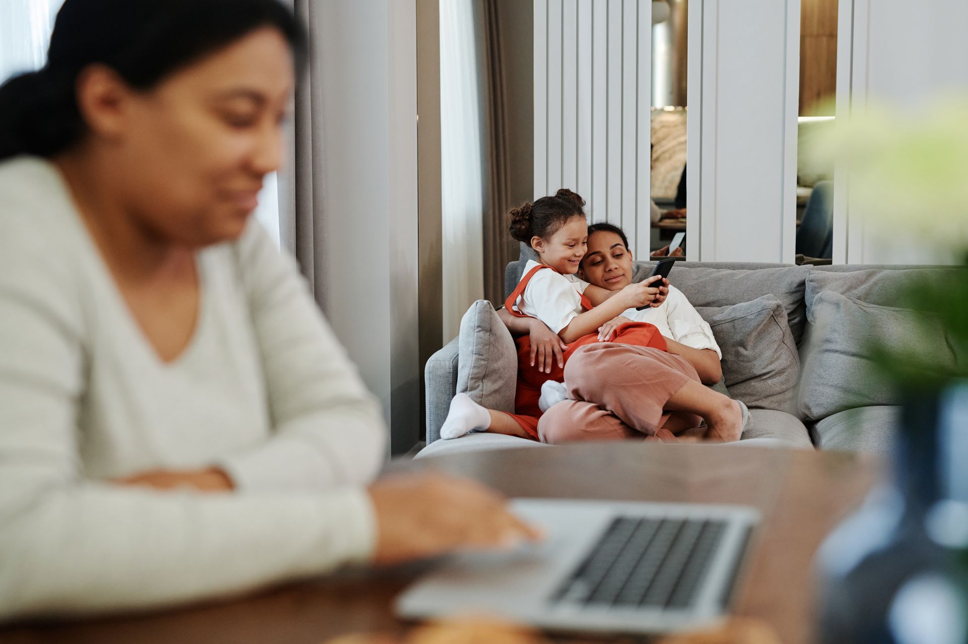 A joyful family moment of bonding and technology use on a cozy sofa.