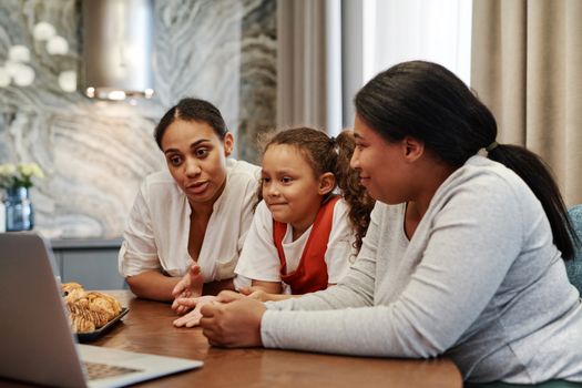 A family enjoying time together watching a video on a laptop indoors.