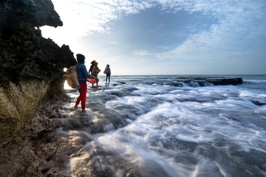 Travelers navigate a rocky coastline with cascading water, showcasing nature's beauty and adventure.