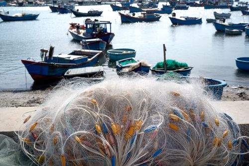 Free A scenic view of fishing boats and nets by the harbor under a bright day sky. Stock Photo