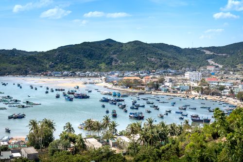 Free A stunning aerial view of a bustling coastal fishing village with boats and lush hills. Stock Photo