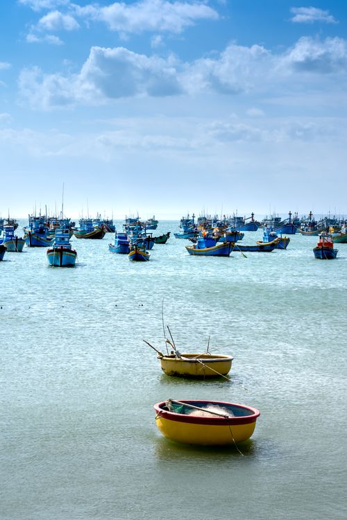 Free A serene view of vibrant boats floating on a calm sea beneath a clear blue sky. Stock Photo