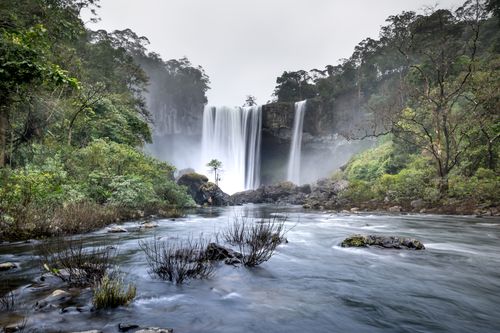 Free Stunning waterfall flowing through a verdant forest, offering serene and natural scenery. Stock Photo