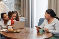 Women Having Conversation with Their Daughter while Sitting Near the Wooden Table