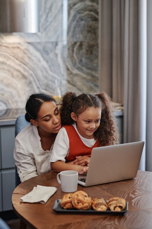 Mother and Daughter Using Laptop and Doing Homework Together 