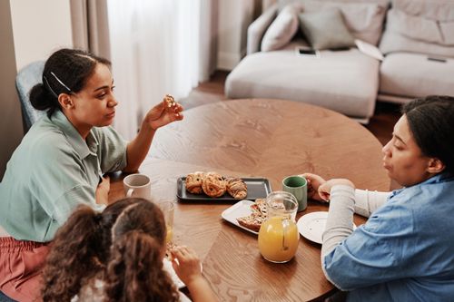Free A cozy morning family breakfast scene with pastries and orange juice at a wooden table. Stock Photo