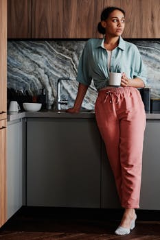 A young woman enjoying leisure time with a mug in a stylish kitchen.