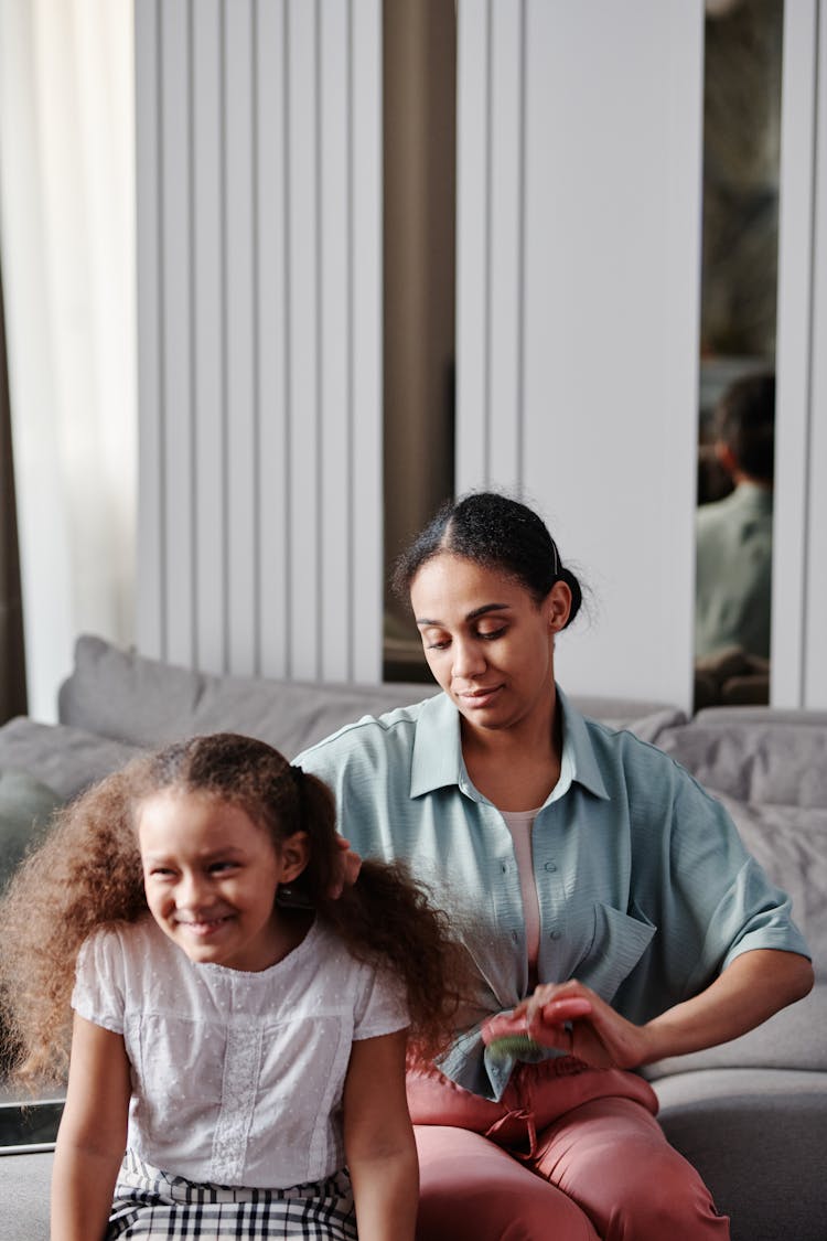 Woman Sitting Behind Girl And Brushing Her Hair