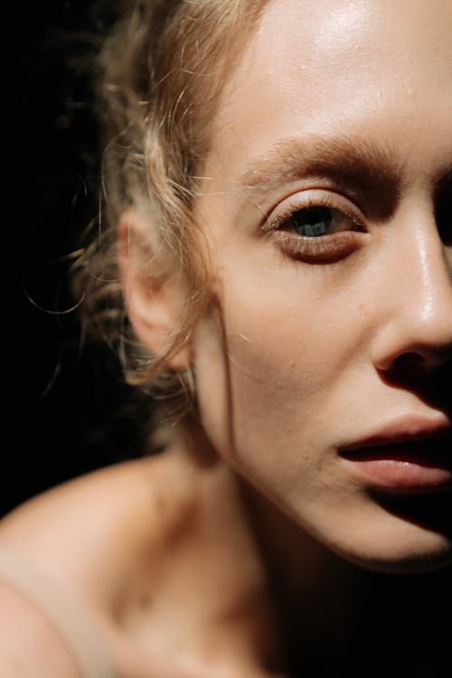 Free Artistic close-up portrait of a woman with dramatic shadow and light contrast Stock Photo