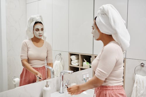 A Woman with Mask on Her Face Looking at the Mirror