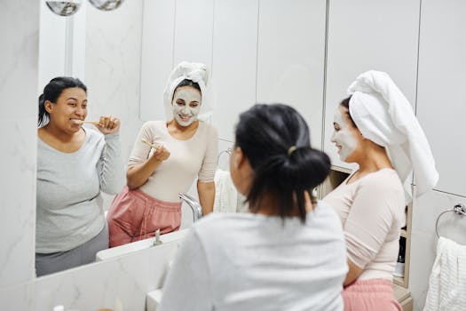 Two women enjoying skincare and oral hygiene routines with smiles in a modern bathroom mirror.
